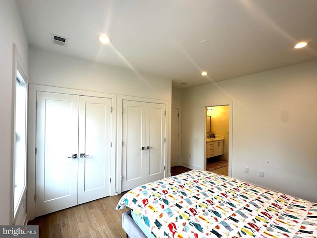 bedroom with recessed lighting, connected bathroom, multiple closets, visible vents, and wood finished floors