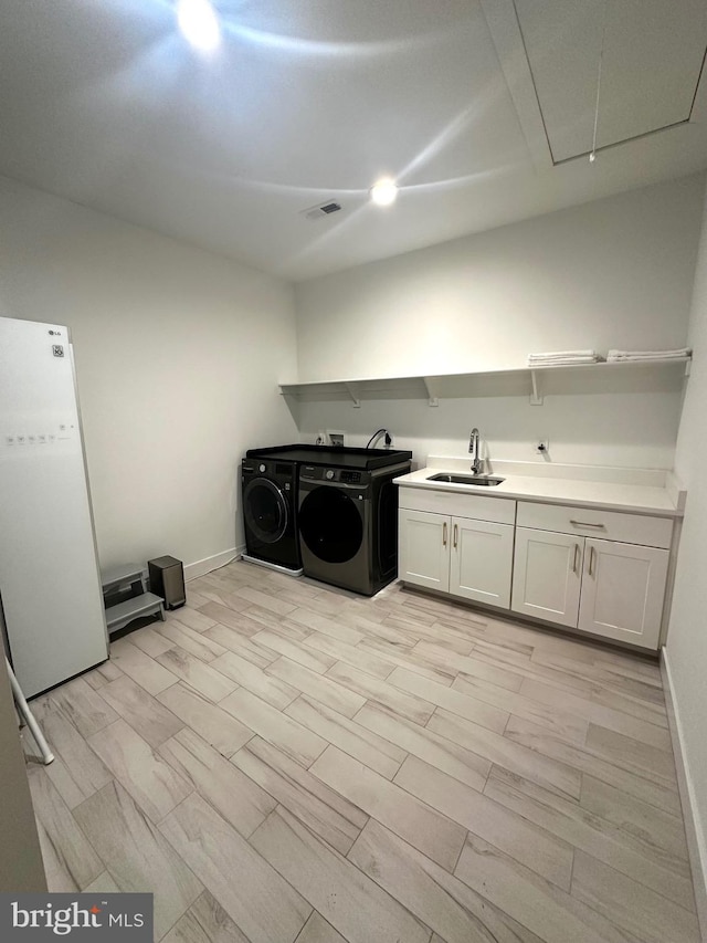 laundry room with attic access, a sink, washing machine and clothes dryer, visible vents, and baseboards