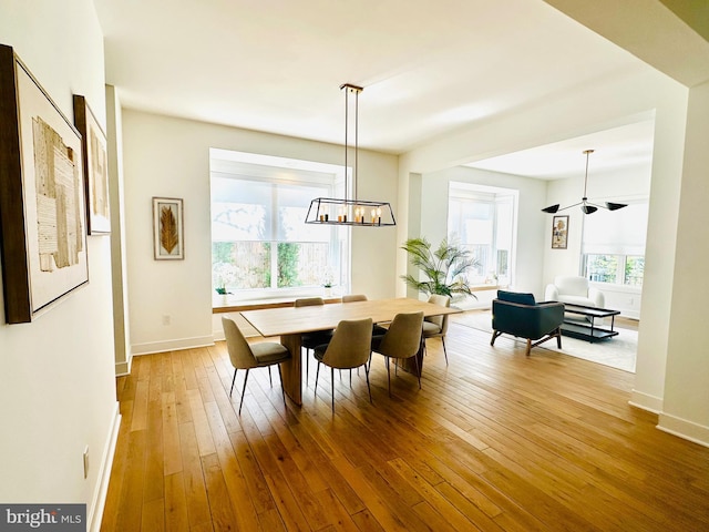 dining area with an inviting chandelier, hardwood / wood-style floors, and baseboards