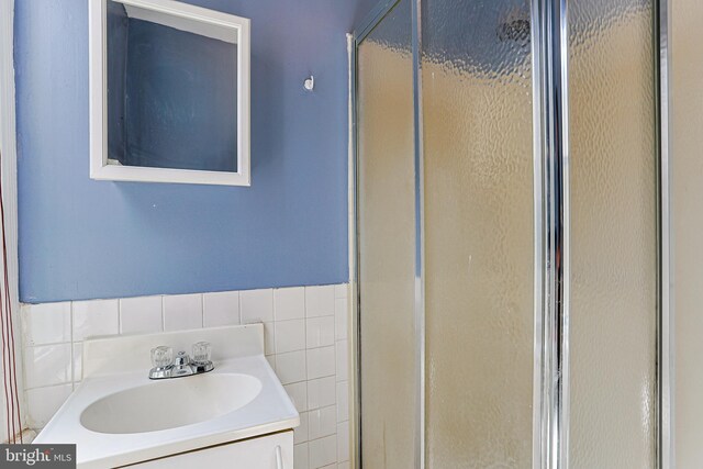 full bathroom with vanity, a shower stall, and tile walls
