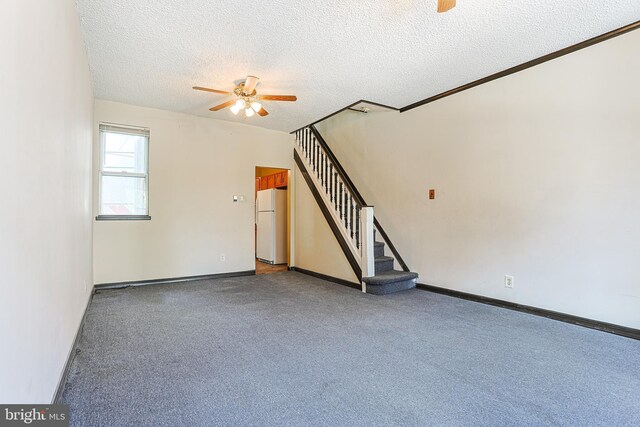unfurnished living room featuring carpet flooring, baseboards, stairway, a ceiling fan, and a textured ceiling