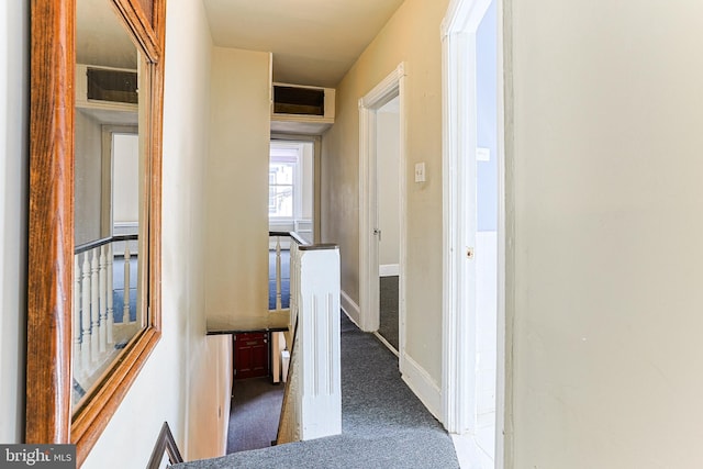 hall featuring an upstairs landing, carpet, and baseboards
