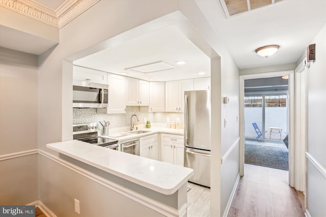kitchen with decorative backsplash, appliances with stainless steel finishes, light wood-type flooring, a sink, and light countertops