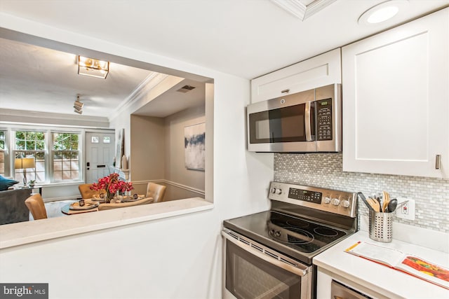 kitchen featuring ornamental molding, light countertops, white cabinets, tasteful backsplash, and appliances with stainless steel finishes