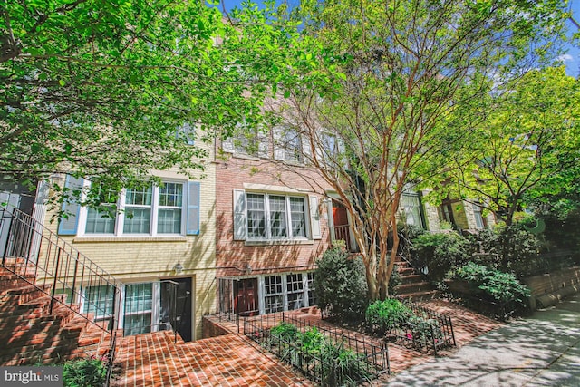 townhome / multi-family property with stairs and brick siding