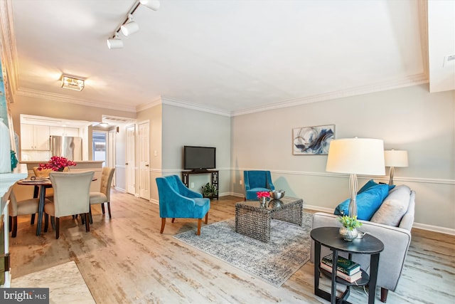living area featuring baseboards, rail lighting, ornamental molding, and wood finished floors