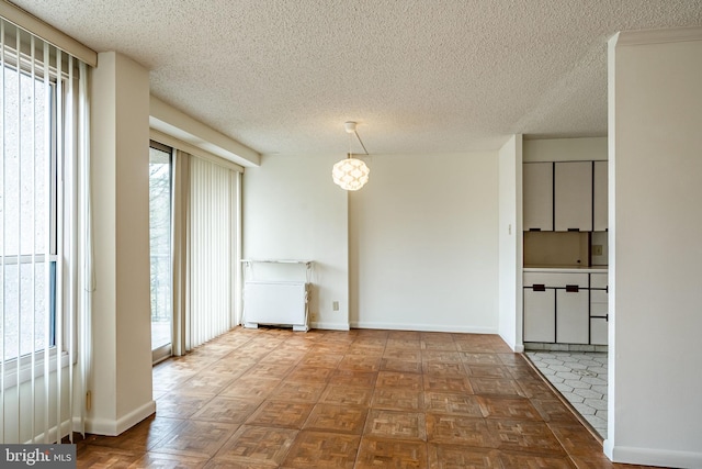 unfurnished room with a healthy amount of sunlight, baseboards, and a textured ceiling