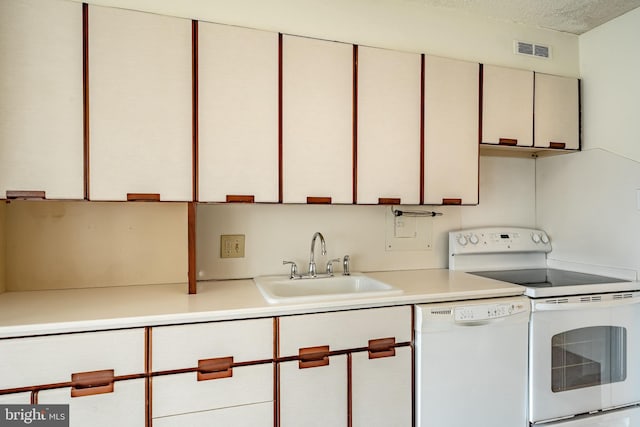 kitchen with a sink, white appliances, light countertops, a textured ceiling, and visible vents