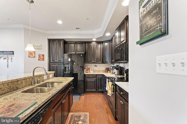 kitchen featuring crown molding, a sink, light stone counters, black appliances, and light wood-style floors