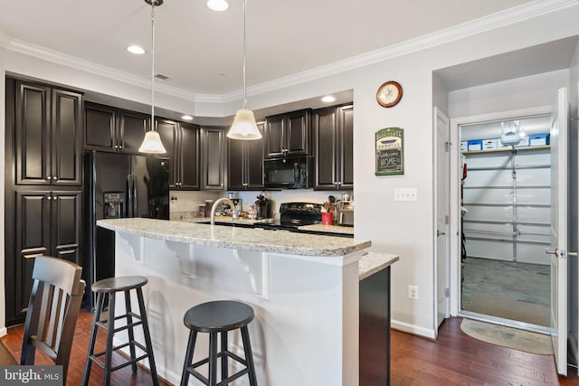kitchen with light stone counters, a kitchen breakfast bar, dark wood-type flooring, ornamental molding, and black appliances