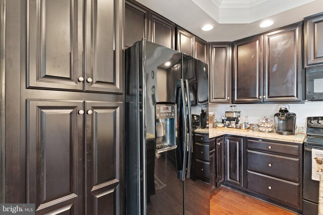 kitchen with ornamental molding, black appliances, wood finished floors, and dark brown cabinets