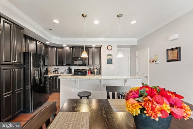 kitchen featuring crown molding, a breakfast bar area, black appliances, and visible vents