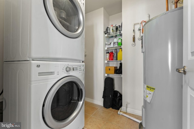 washroom with laundry area, light tile patterned floors, baseboards, stacked washing maching and dryer, and water heater
