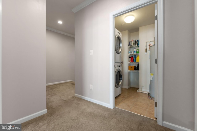 clothes washing area featuring stacked washing maching and dryer, baseboards, ornamental molding, and carpet flooring