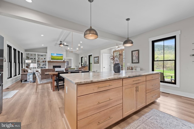 kitchen featuring light brown cabinetry, a fireplace, vaulted ceiling with beams, light wood-style flooring, and decorative light fixtures