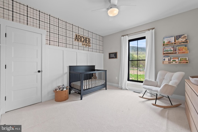 carpeted bedroom with ceiling fan, visible vents, a crib, and baseboards