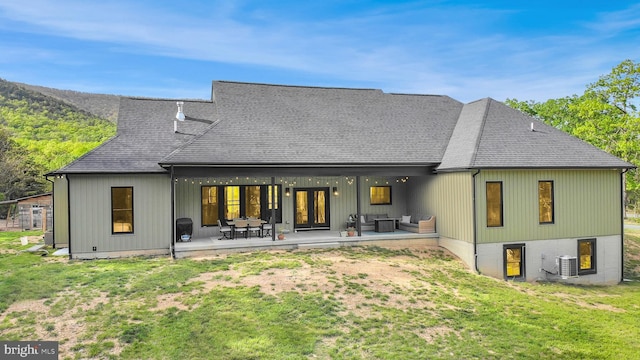 back of house with a lawn, a shingled roof, central air condition unit, and french doors