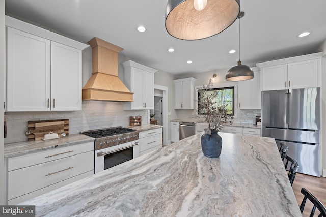 kitchen with custom exhaust hood, recessed lighting, white cabinetry, tasteful backsplash, and stainless steel appliances