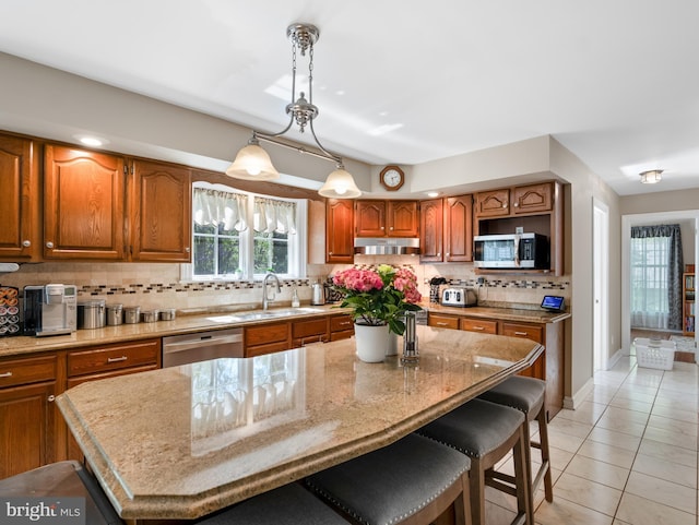 kitchen featuring appliances with stainless steel finishes, decorative backsplash, brown cabinetry, and a sink