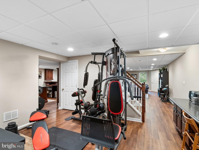 exercise room featuring visible vents, baseboards, a drop ceiling, recessed lighting, and wood finished floors