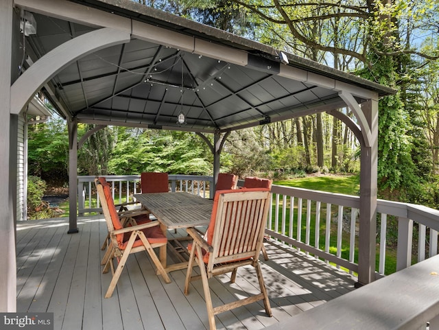 wooden terrace featuring outdoor dining area and a gazebo