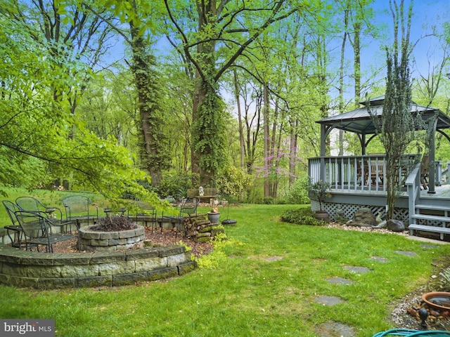 view of yard featuring a deck, a gazebo, and an outdoor fire pit