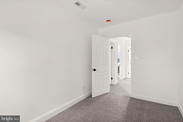 empty room with baseboards, visible vents, and carpet flooring