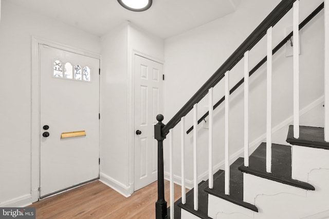 foyer entrance with baseboards, stairway, and light wood-style flooring