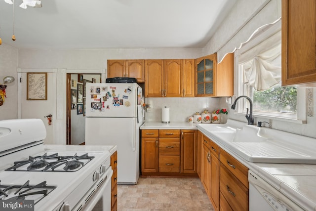 kitchen with light countertops, glass insert cabinets, brown cabinetry, and white appliances