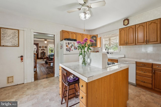 kitchen featuring brown cabinets, a ceiling fan, a healthy amount of sunlight, and dishwasher
