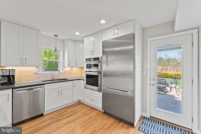 610 Valley Brook Dr, Silver Spring, MD 20904 - kitchen with decorative backsplash, a sink, white cabinets, light wood finished floors, and stainless steel appliances