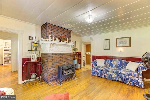 living room featuring a wood stove, wood finished floors, wainscoting, and wood walls
