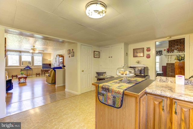 kitchen featuring a ceiling fan, light stone countertops, and baseboards