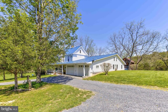 farmhouse-style home with driveway, a front yard, and metal roof