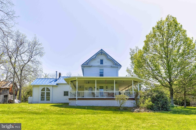 rear view of house with a lawn, metal roof, and a porch