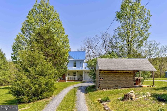 view of front of home featuring covered porch, dirt driveway, a front yard, and metal roof