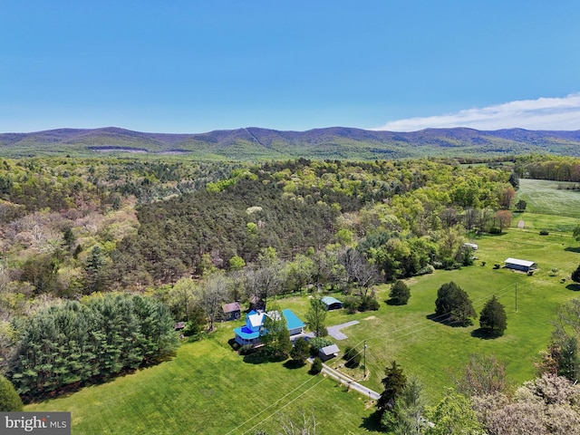 view of rural area featuring a mountain backdrop and a heavily wooded area