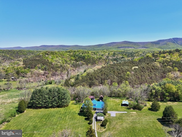 view of subject property with a mountainous background and a heavily wooded area
