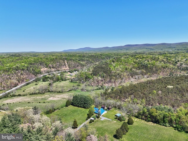 aerial view of property and surrounding area featuring a heavily wooded area and a mountainous background