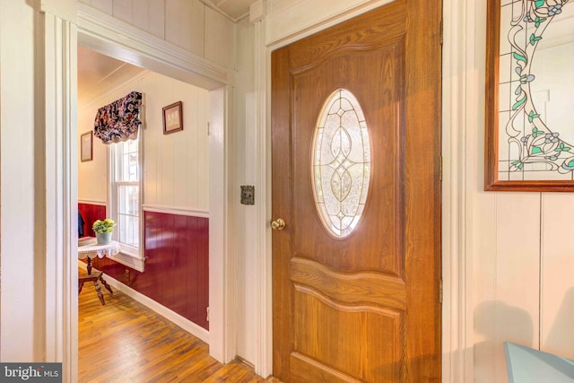 foyer entrance with wood finished floors and crown molding