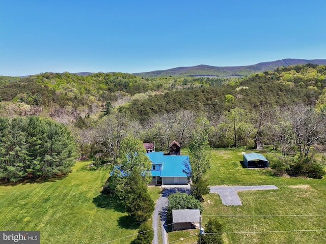 view of subject property featuring a mountainous background and a heavily wooded area