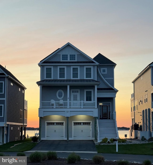 beach home featuring a standing seam roof, aphalt driveway, metal roof, and an attached garage