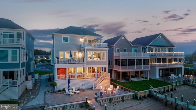 29710 Seagrass Ct, Dagsboro, DE 19939 - back of house at dusk featuring a balcony, stairway, and a patio