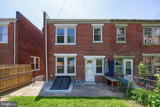 view of front facade with a fenced backyard, a patio, and brick siding