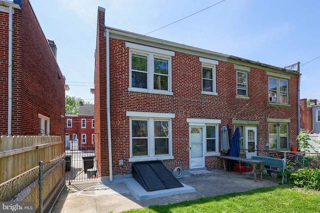 back of property featuring fence, a gate, a patio, and brick siding