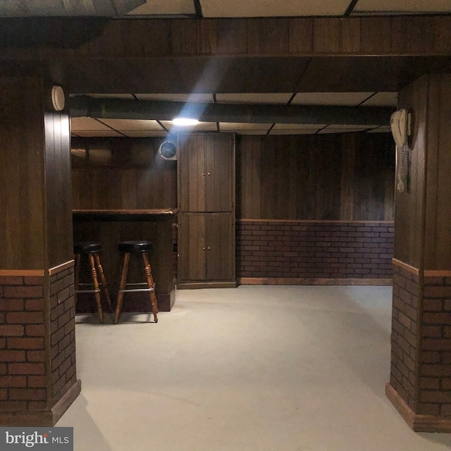 finished below grade area featuring wood walls and a bar