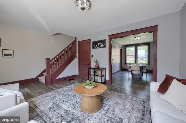 living room featuring baseboards, visible vents, wood finished floors, and stairway