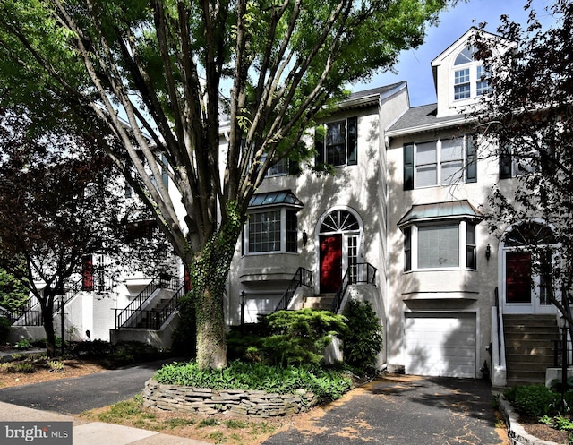 townhome / multi-family property featuring a garage, driveway, stairs, and stucco siding