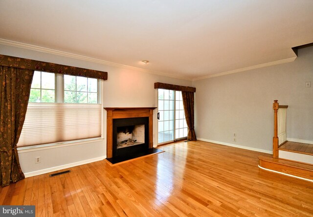 unfurnished living room with visible vents, ornamental molding, wood finished floors, and a wealth of natural light