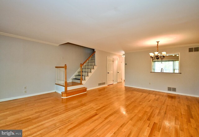 unfurnished living room with a notable chandelier, light wood-type flooring, and visible vents
